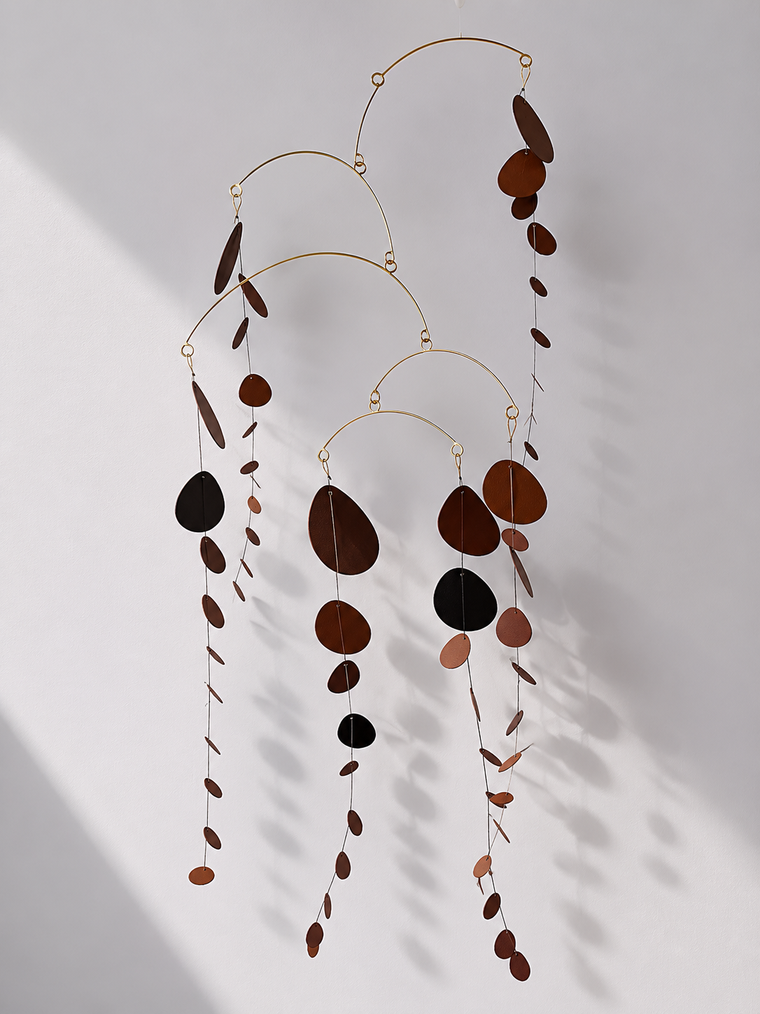 Decorative hanging mobile with brown and black circular elements on a light gray background