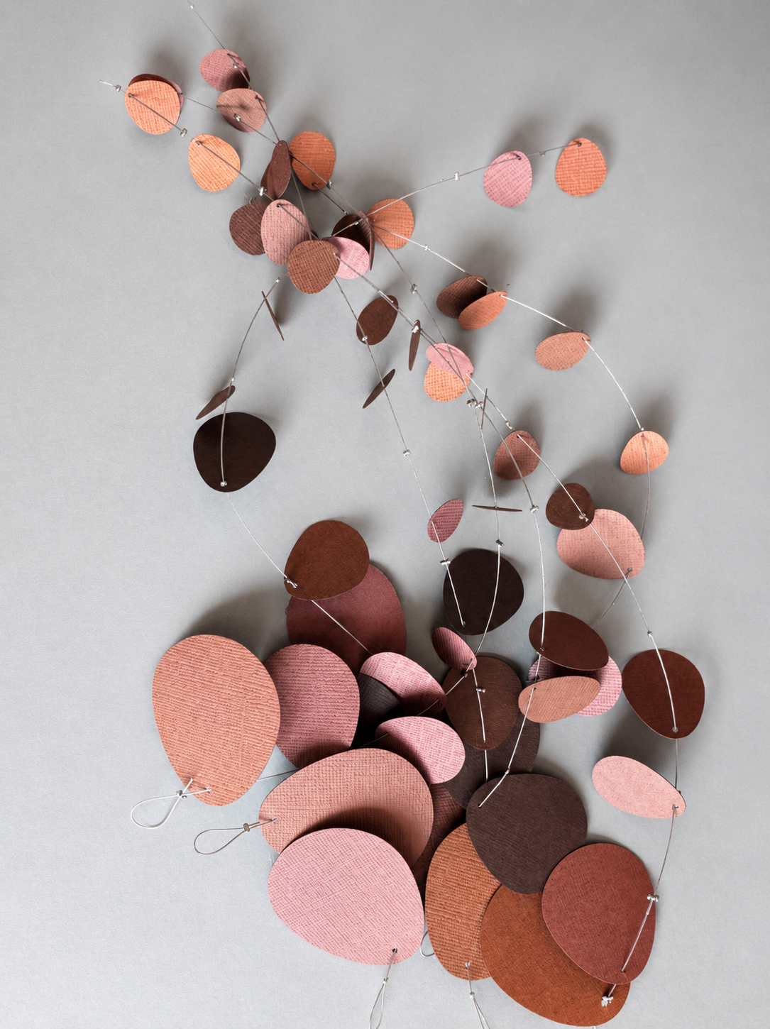 Decorative string with pink, brown, and red leaf-shaped beads on a gray background