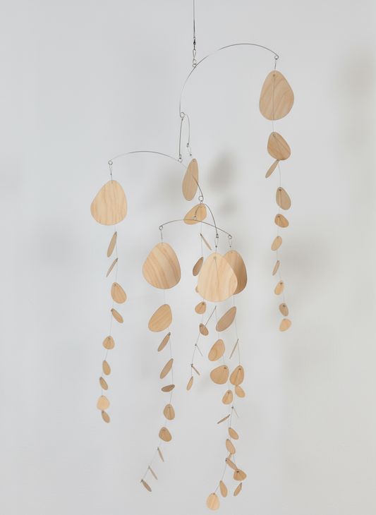 Decorative hanging mobile with wooden leaf shapes on a plain background